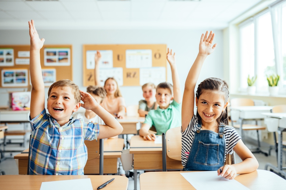 Group of children in school raising their hands